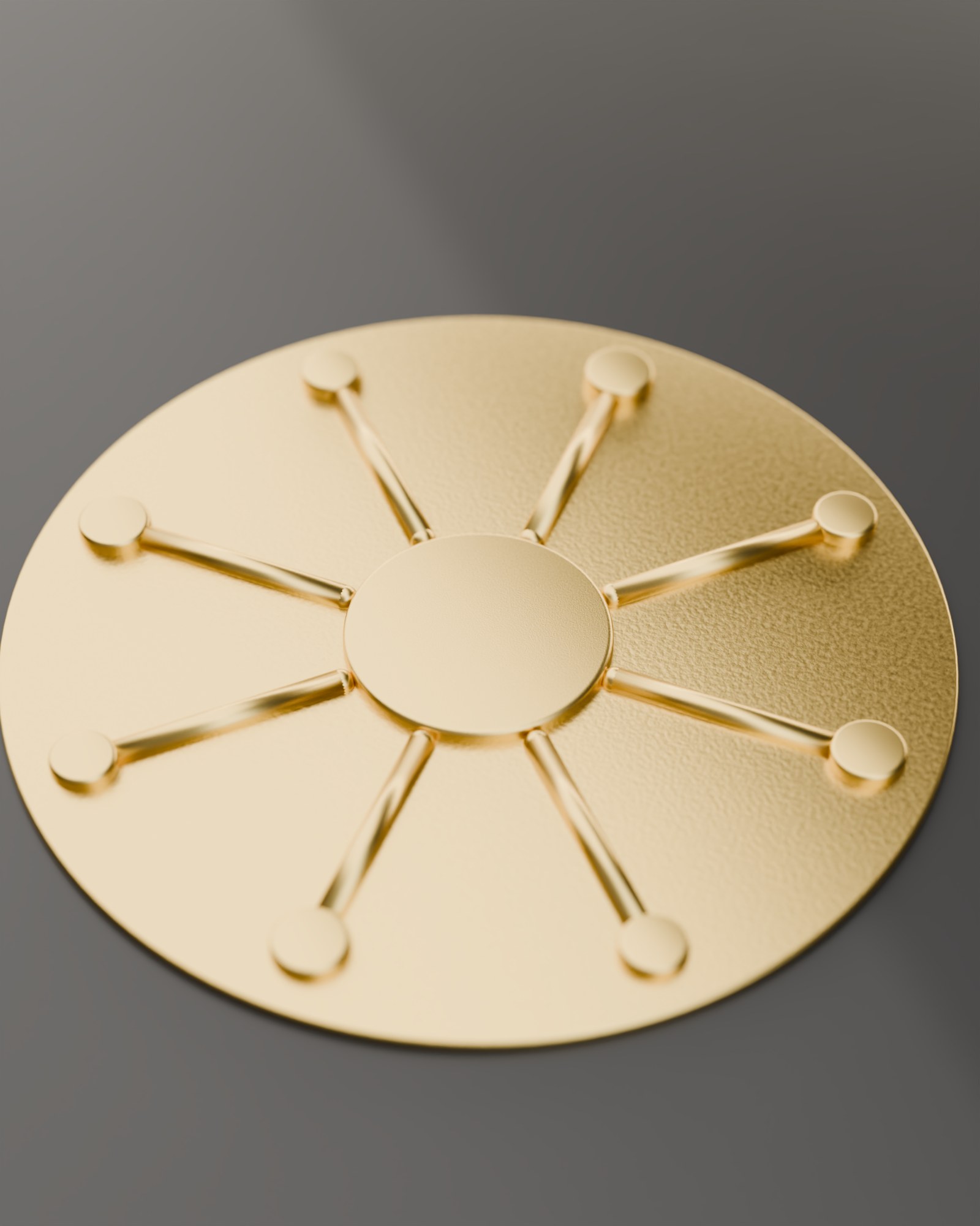 The Web Conductors sun-mark, cast in brass, on dark stone